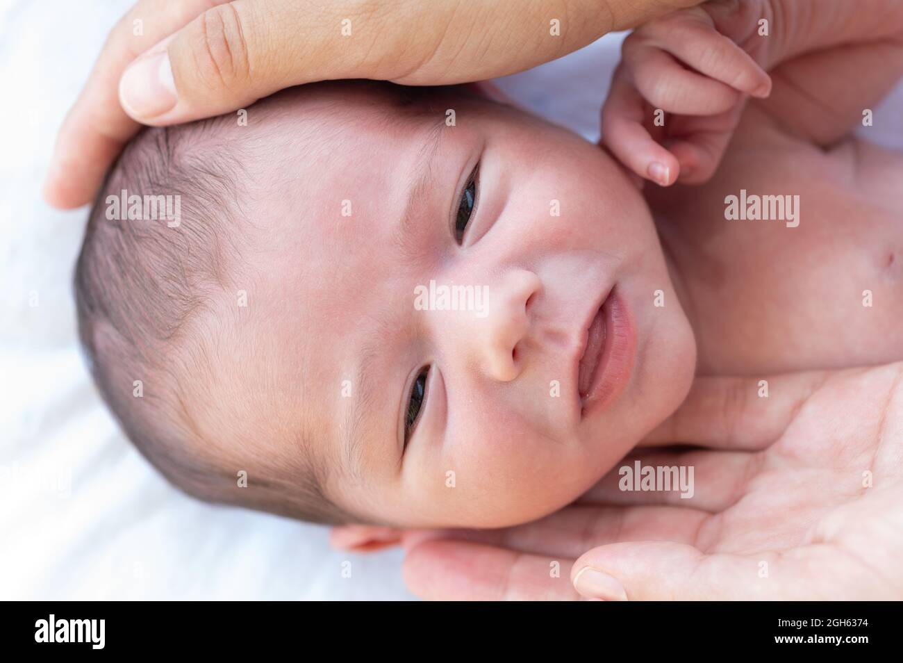 Primo piano di raccolto anonima madre toccare testa di bambino carino sorridente e guardando la macchina fotografica Foto Stock