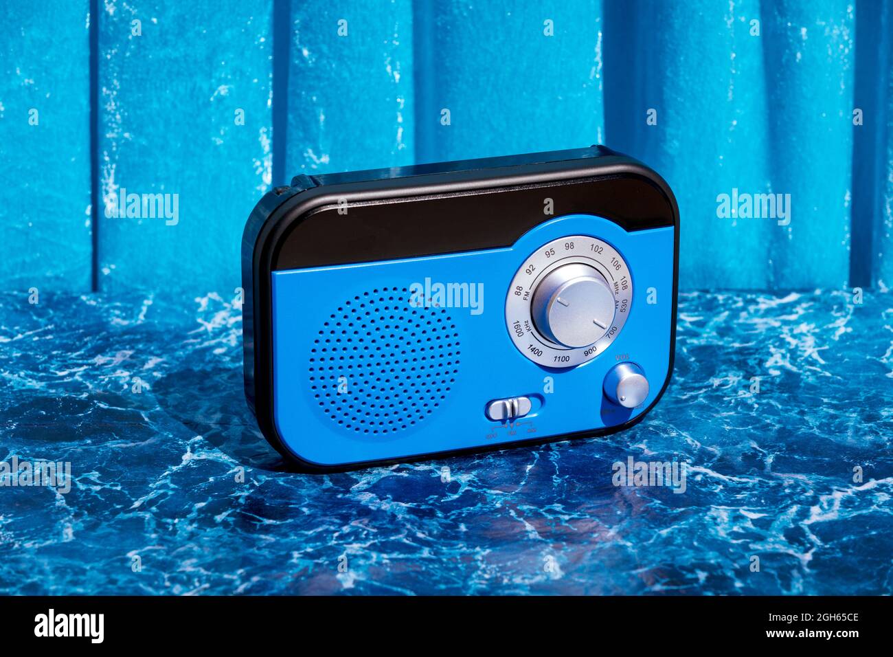 Ricevitore radio retro lucido posizionato su un tavolo in marmo su sfondo blu in studio Foto Stock