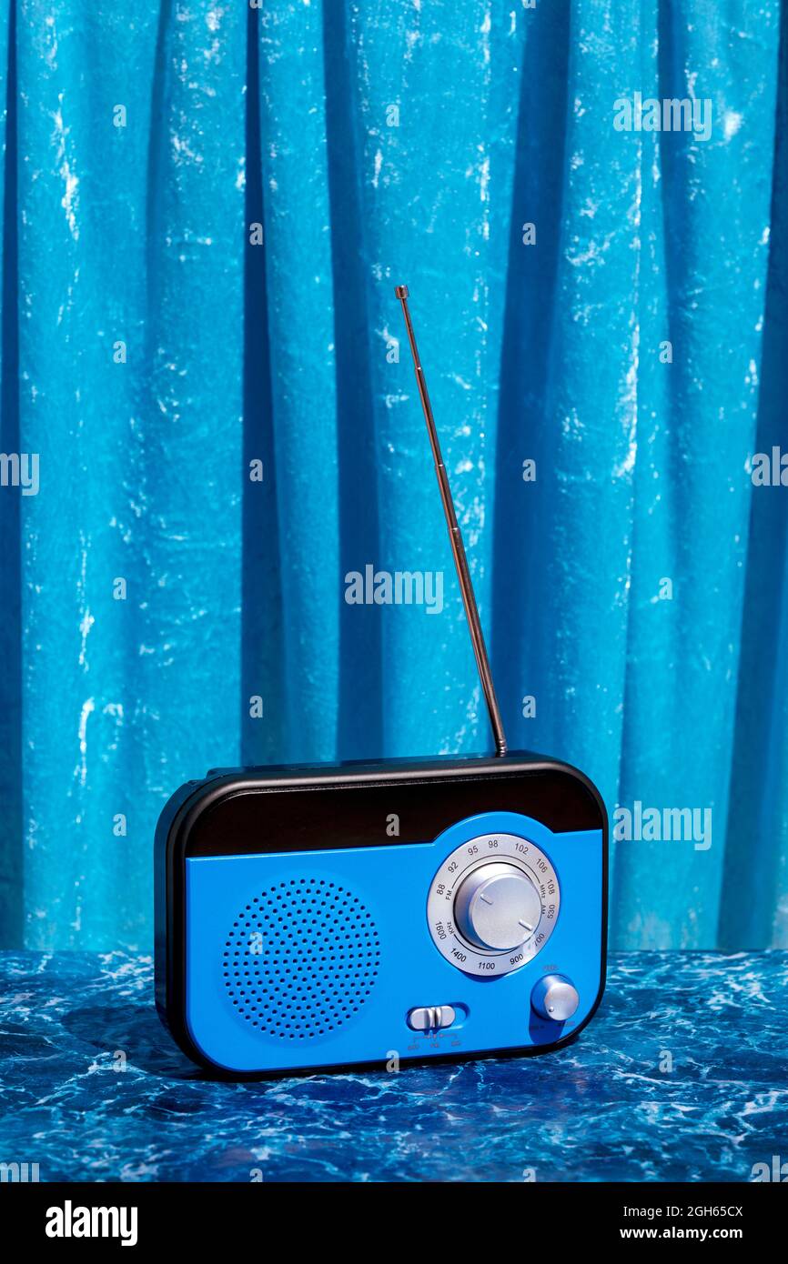 Ricevitore radio retro lucido posizionato su un tavolo in marmo su sfondo blu in studio Foto Stock