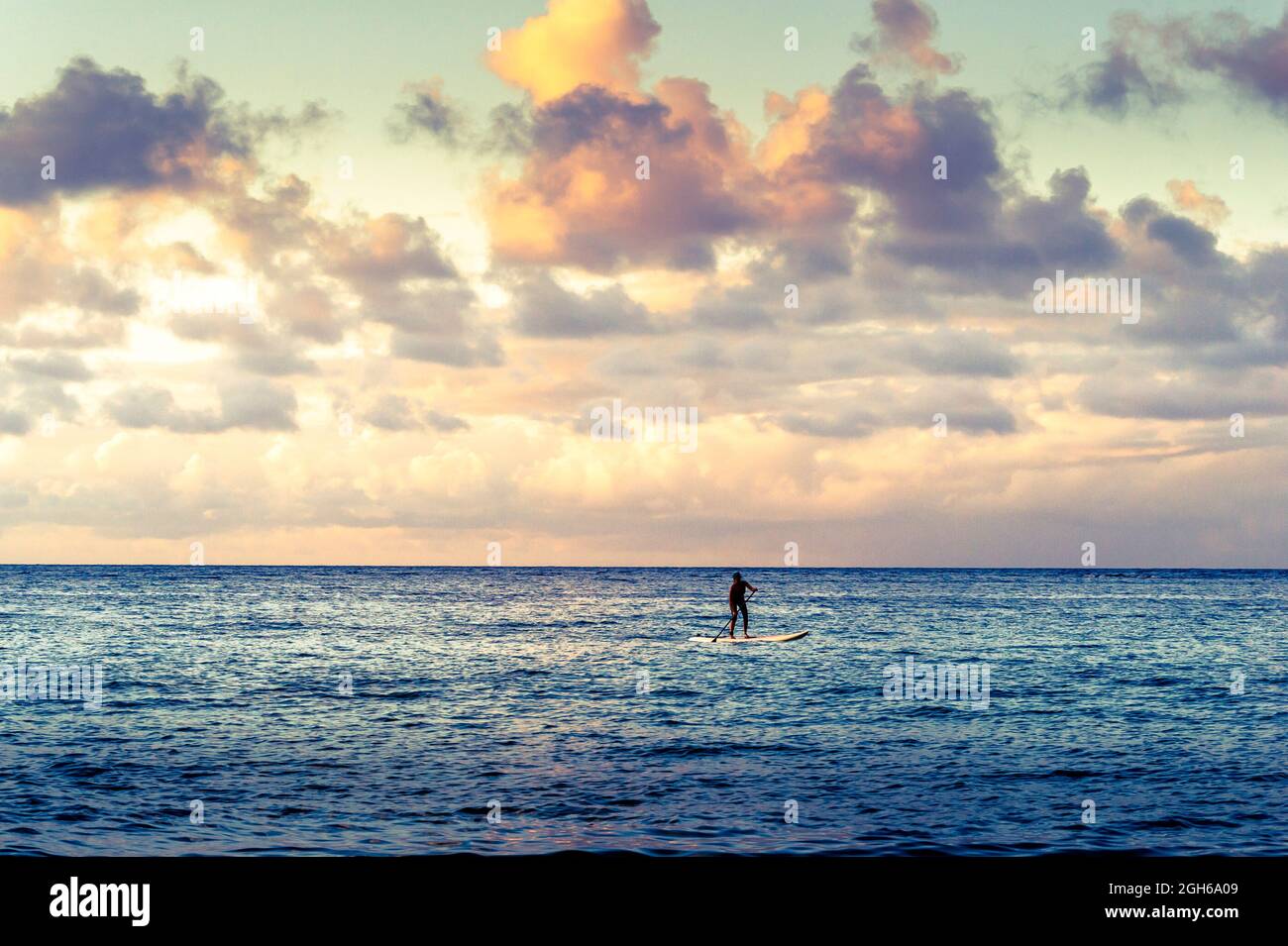 Il solitario paddleboarder galleggia lontano dalla riva dell'isola di Oahu, Hawaii Foto Stock