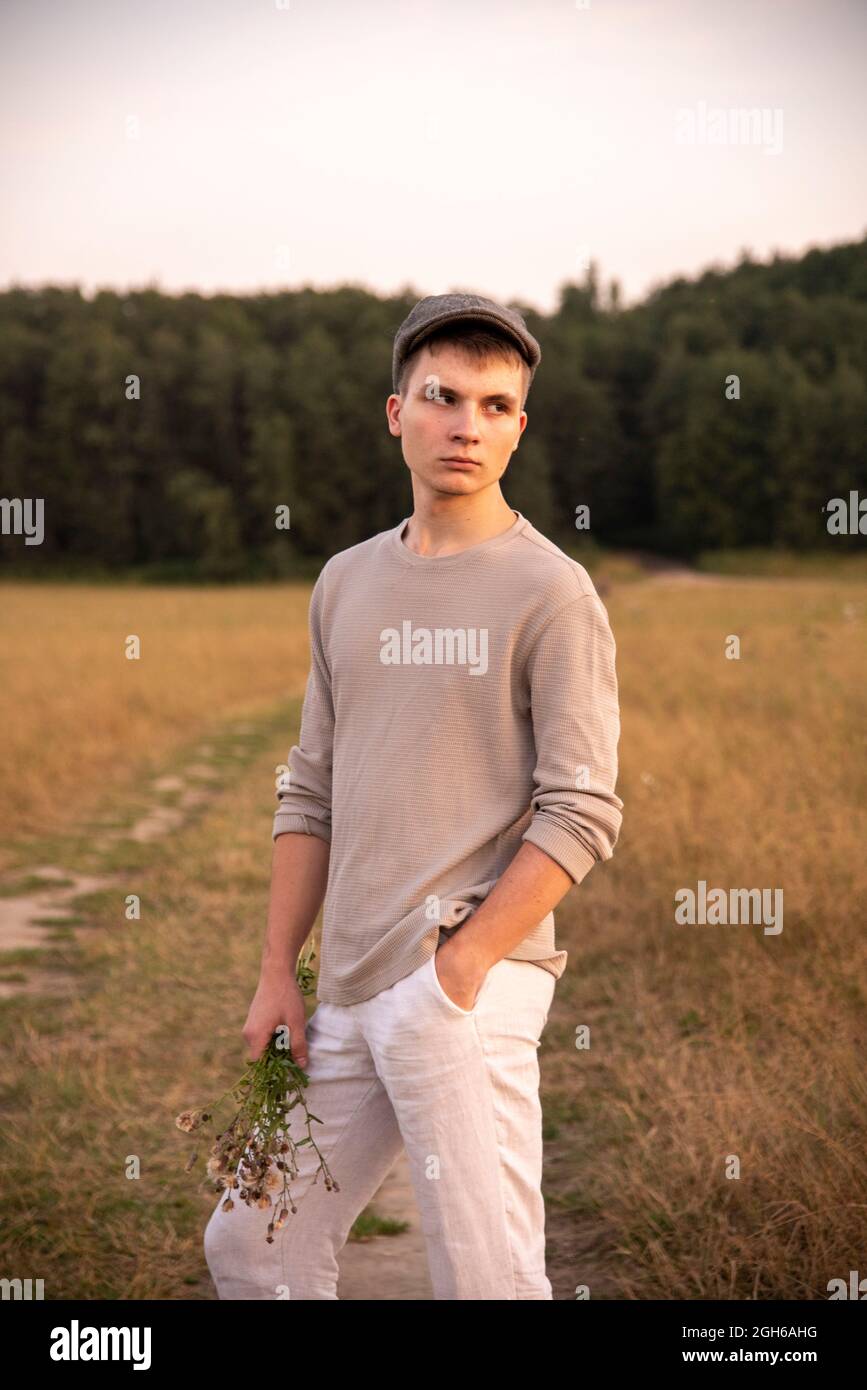 Ritratto di un ragazzo di 18 anni in un cappello, in piedi su una strada  sterrata nel mezzo di un campo Foto stock - Alamy