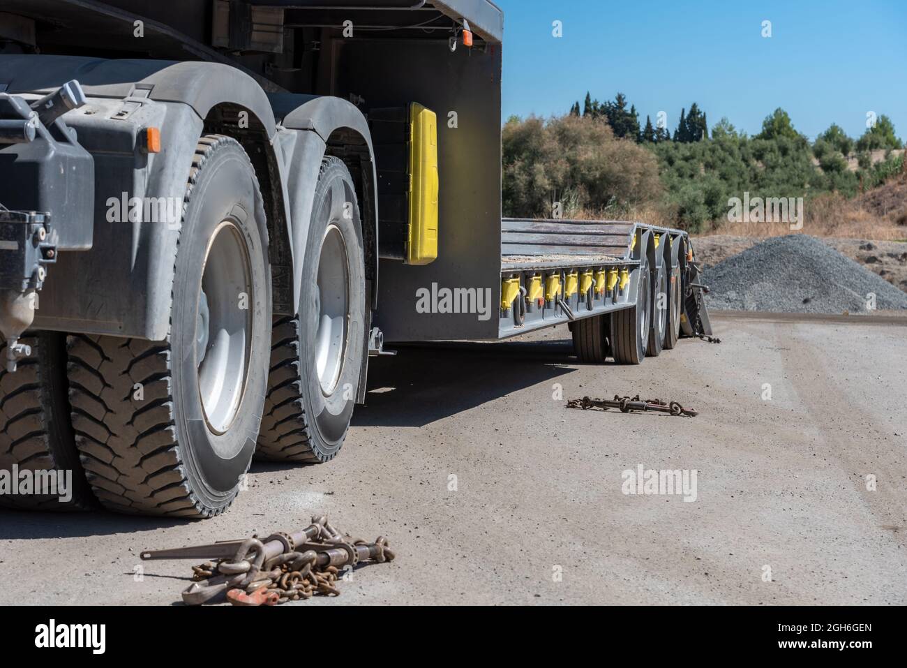 Carrello con trazione a doppio assale e piattaforma per il trasporto di macchinari per costruzioni pesanti. Foto Stock