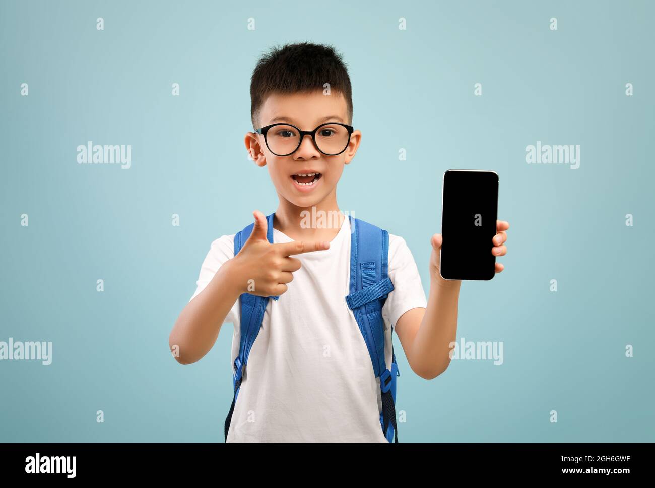 App didattica. Emozionato studente asiatico che punta allo smartphone con schermo nero vuoto Foto Stock