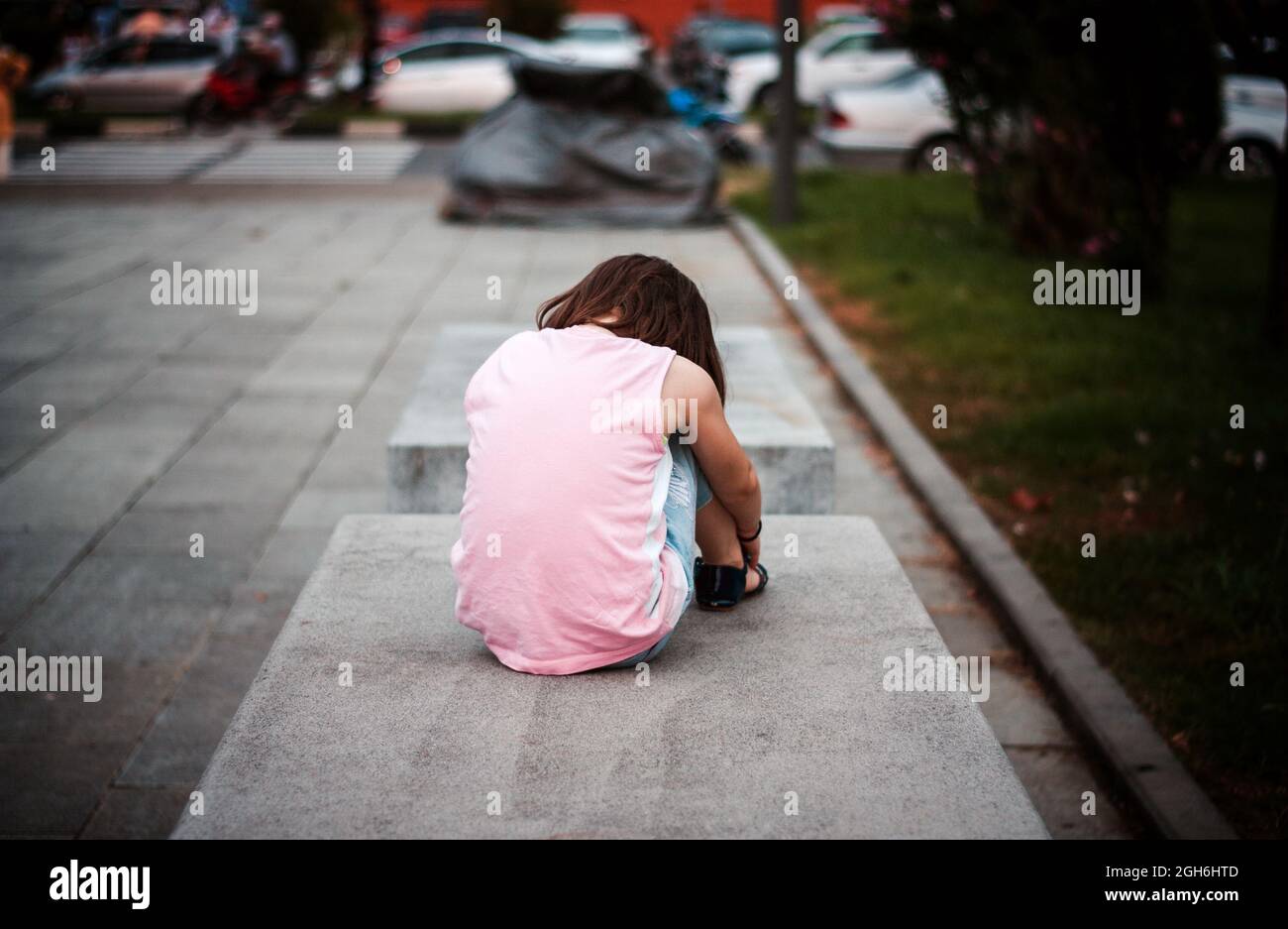 Bambina seduta da sola sulla panchina Foto Stock