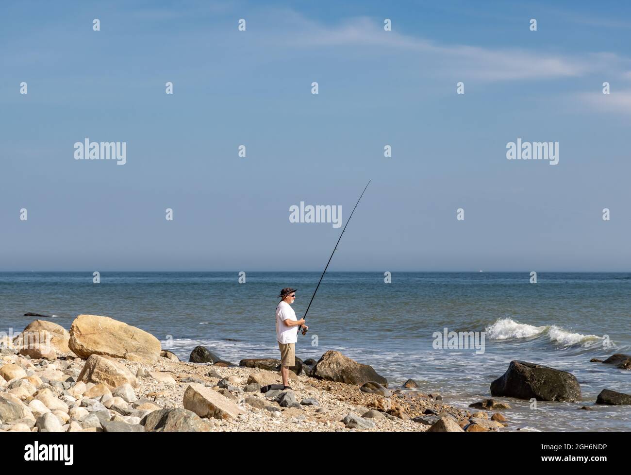 Un uomo che pesca con la canna e bobina fuori Montauk Point, NY Foto Stock