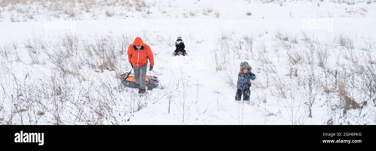 felice famiglia, padre e bambini figlio e figlia attività trascorrere le loro vacanze invernali nevoso divertirsi e cavalcare gli scivoli in natura all'aperto. ban Foto Stock