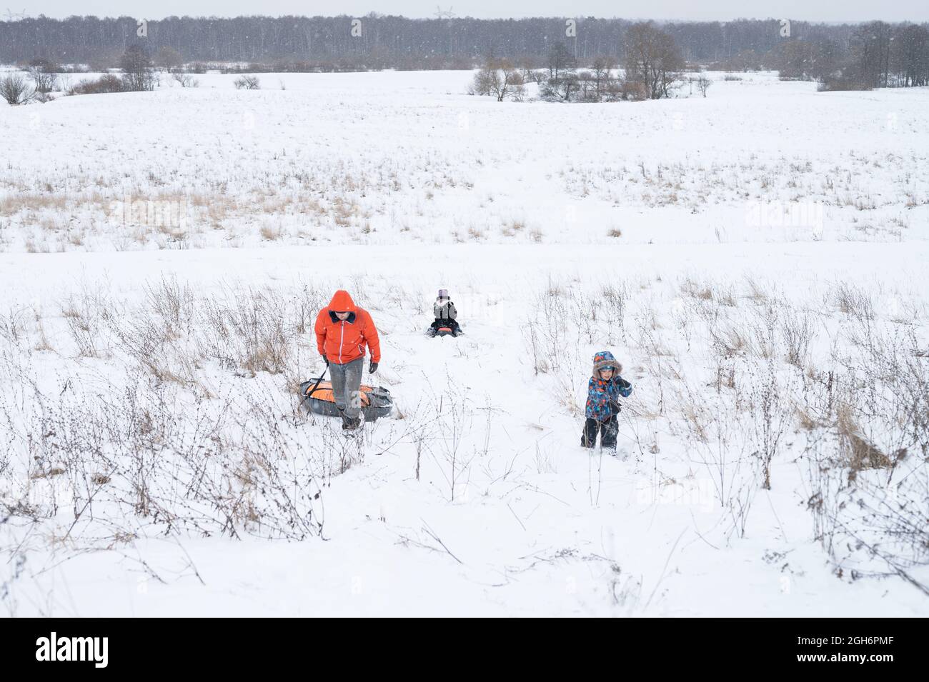 felice famiglia, padre e bambini figlio e figlia attività trascorrere le loro vacanze invernali nevoso divertirsi e cavalcare gli scivoli nella natura all'aperto Foto Stock