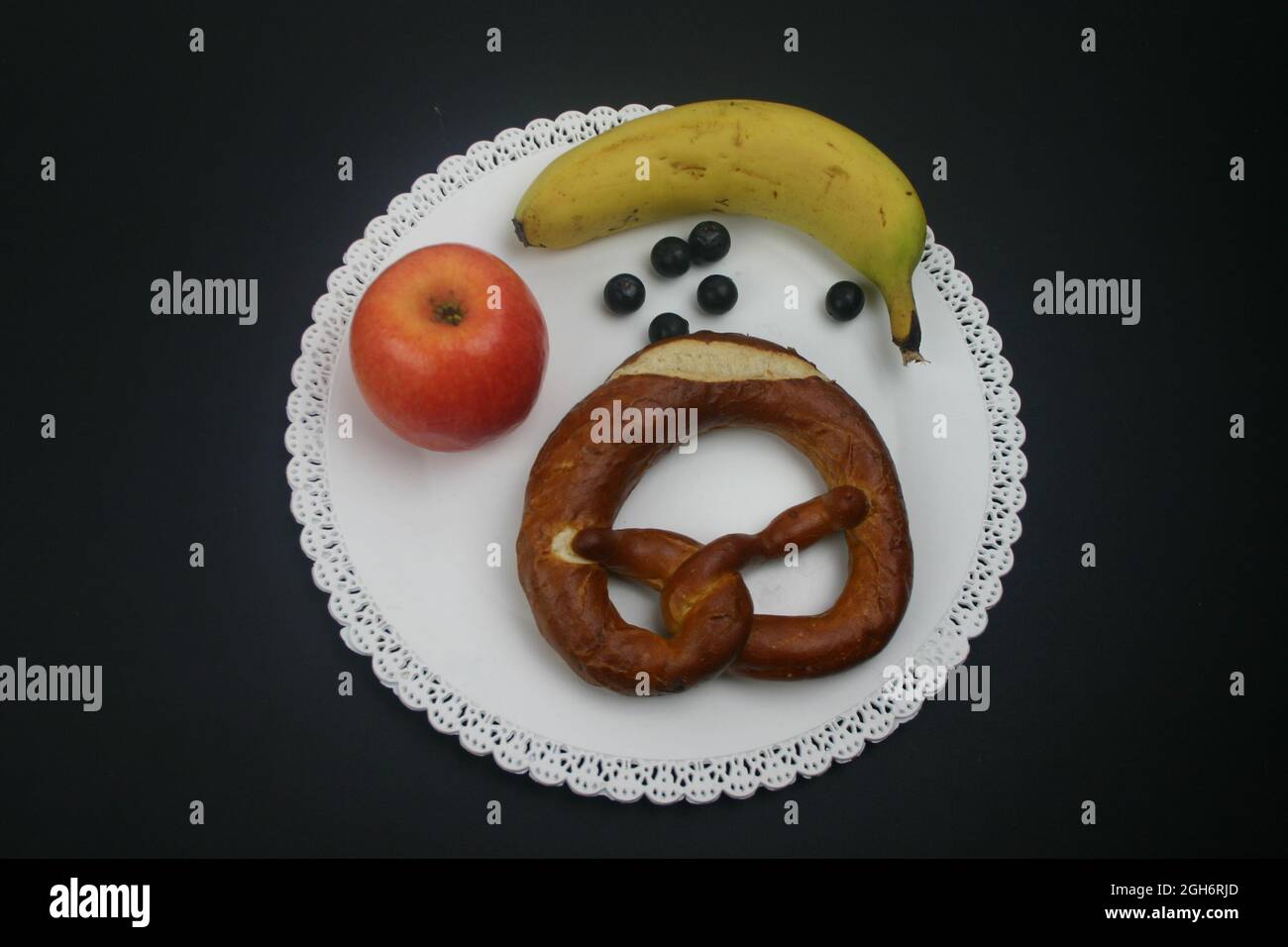 Essen Früchte und eine Brezel auf einen weißen Teller Foto Stock