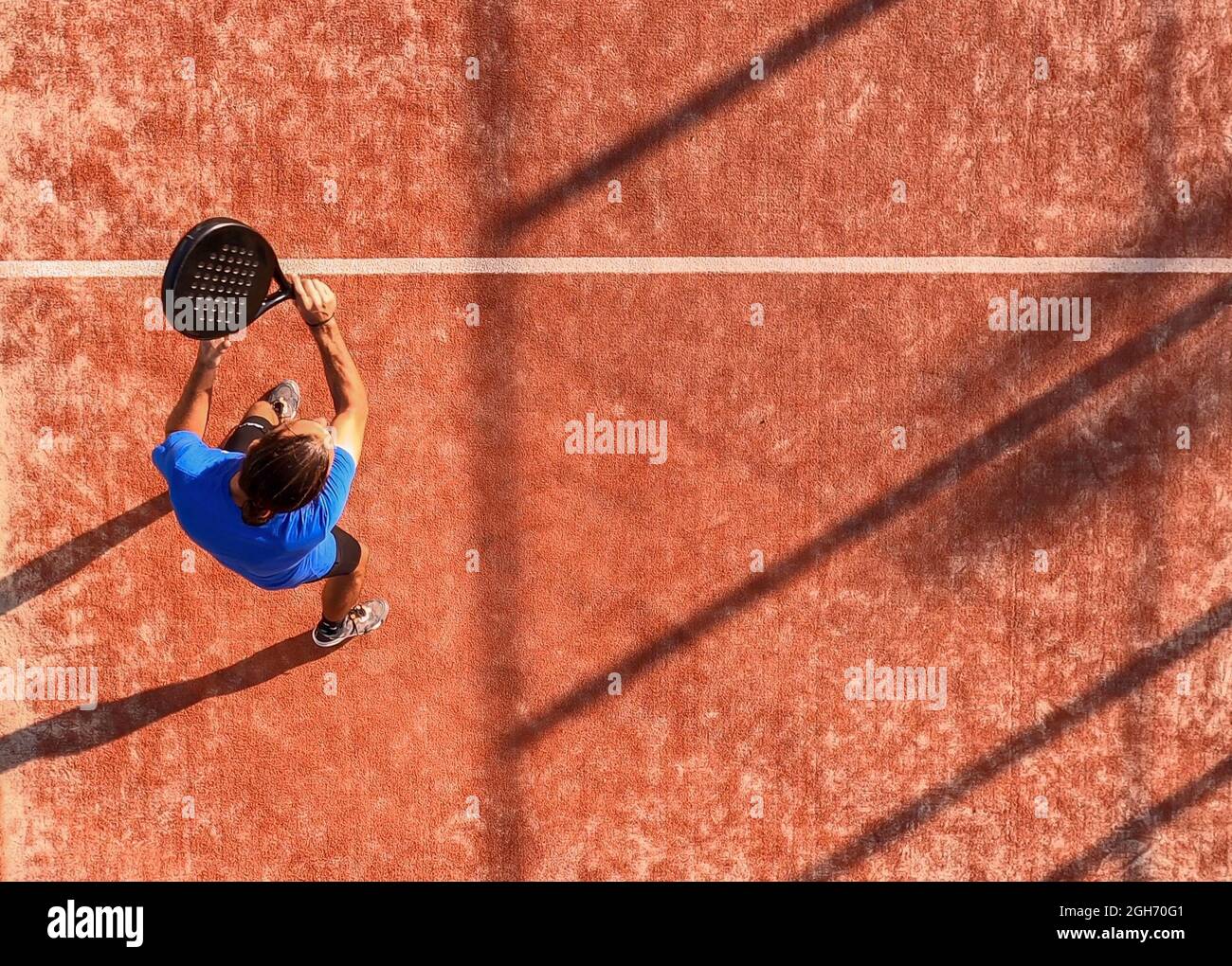 Vista dall'alto di un giocatore professionista di paddle tennis che ha appena colpito la palla con la racchetta. Partita di padel su un campo all'aperto. Foto Stock