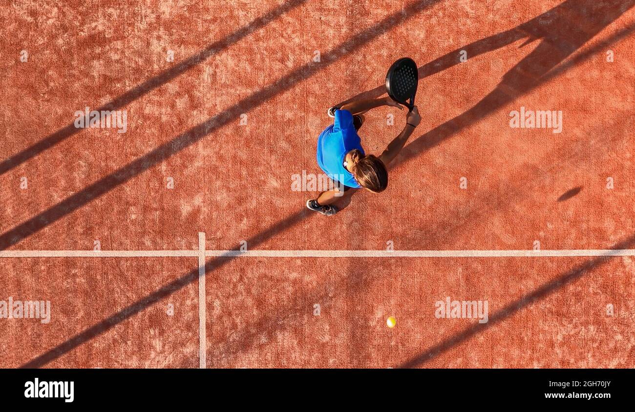 Vista dall'alto di un giocatore professionista di paddle tennis che sta andando colpire la palla con la racchetta su un campo all'aperto. Foto Stock