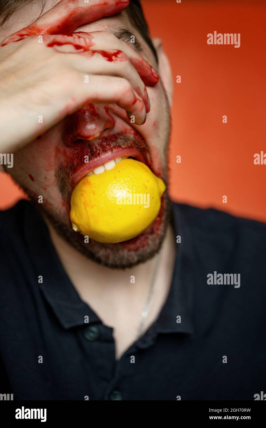 ritratto creativo di un uomo con un limone su sfondo rosso Foto Stock