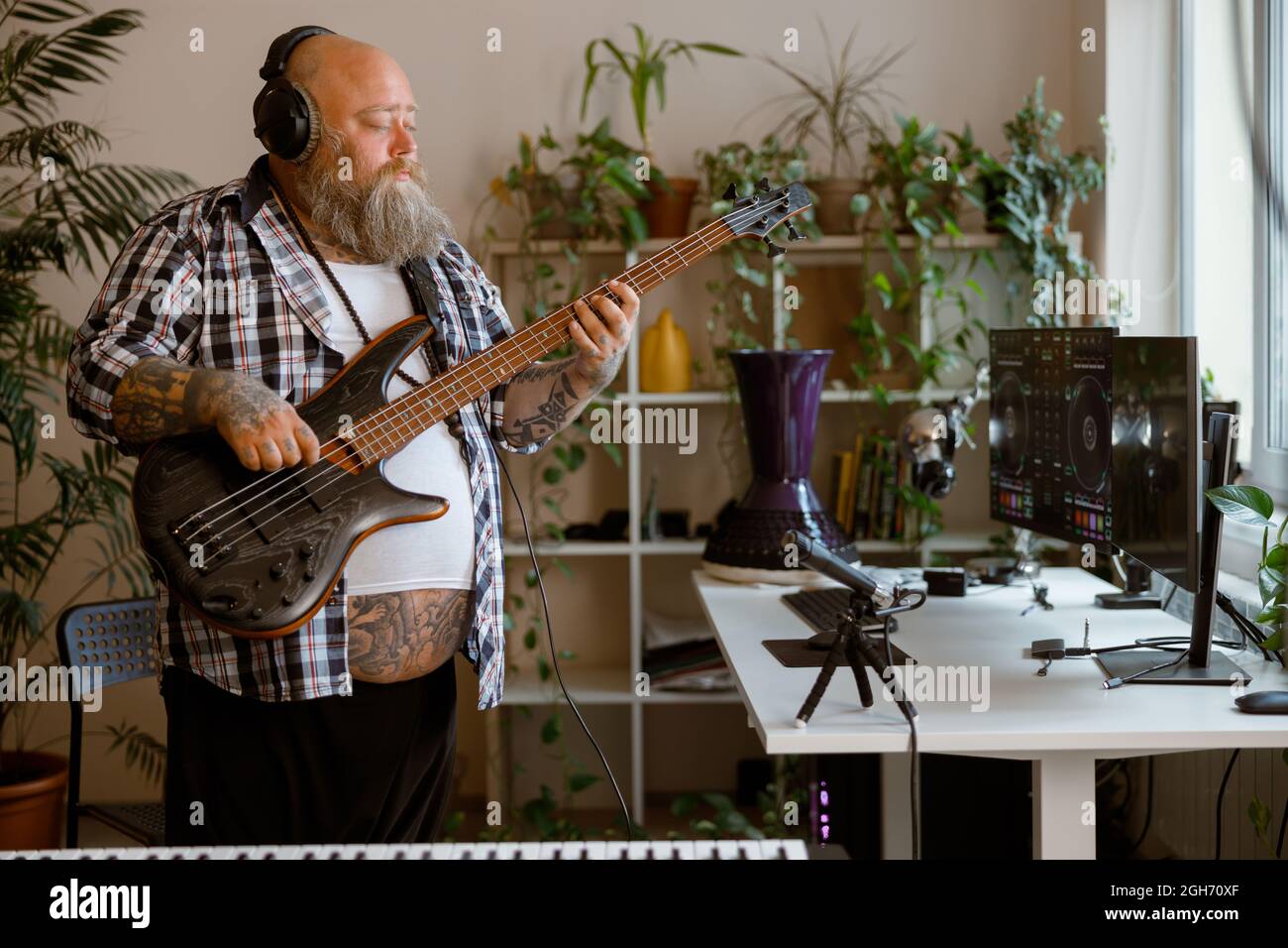 Il compositore maturo suona la traccia di registrazione di chitarra bas sul posto di lavoro in studio domestico Foto Stock