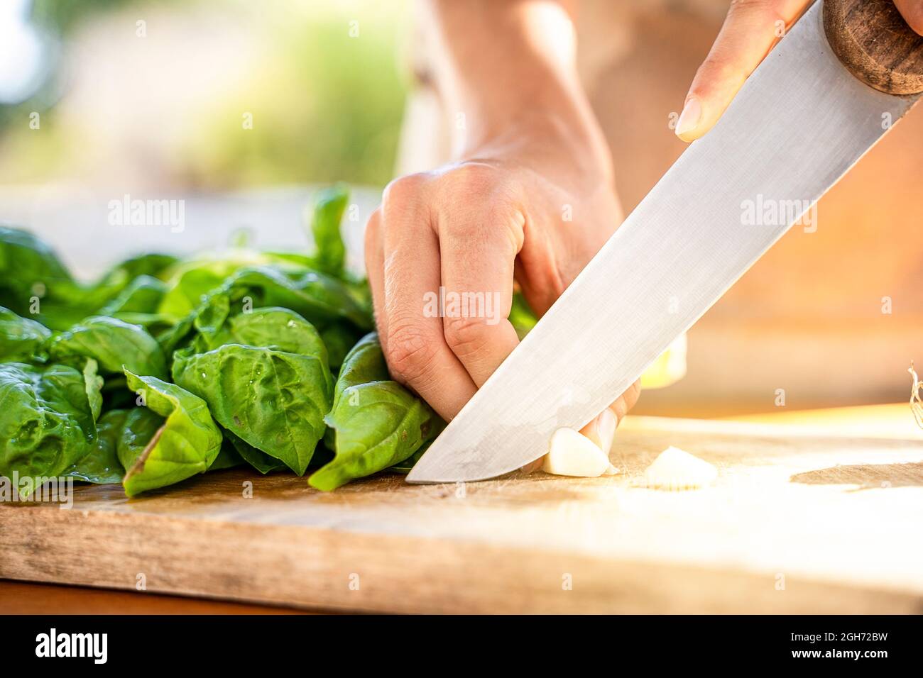 Taglio del basilico fresco su un tagliere per la salsa di pesto genovese Foto Stock