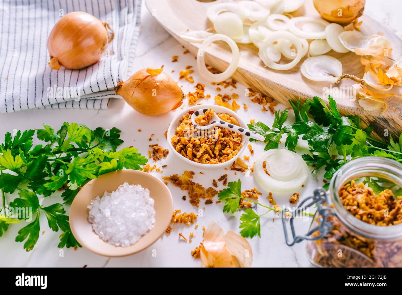Preparazione di cipolle fritte fatte in casa con ingredienti sul tavolo da cucina bianco Foto Stock