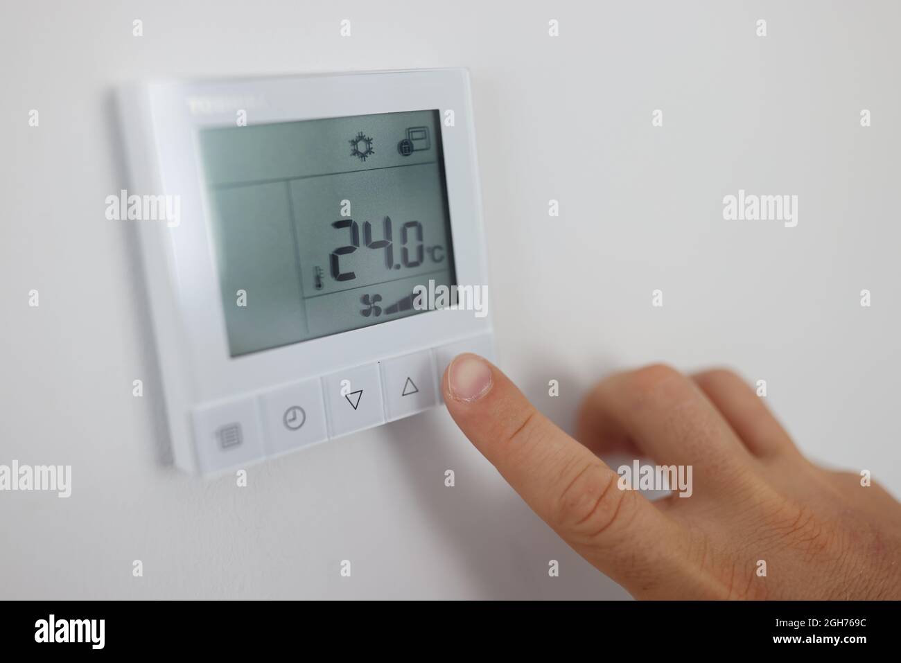 La persona regola la temperatura dell'aria nell'ambiente tramite il telecomando a parete Foto Stock