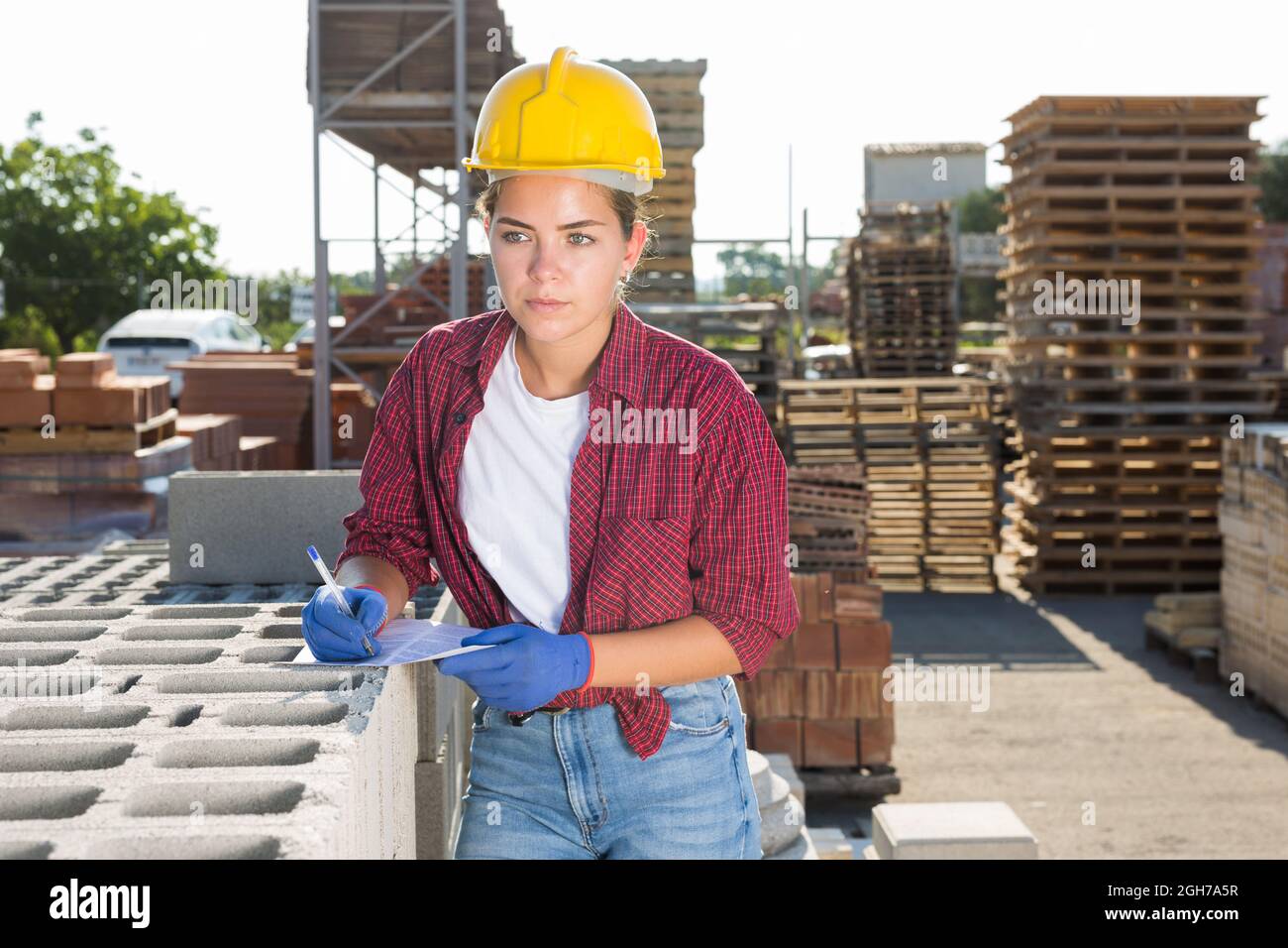 Lavoratrice femminile che controlla la quantità di mattoni in magazzino Foto Stock