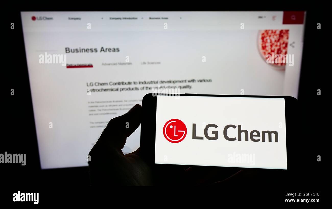 Persona che tiene uno smartphone con il logo della società chimica sudcoreana LG Chem Ltd. Sullo schermo di fronte al sito web. Mettere a fuoco sul display del telefono. Foto Stock