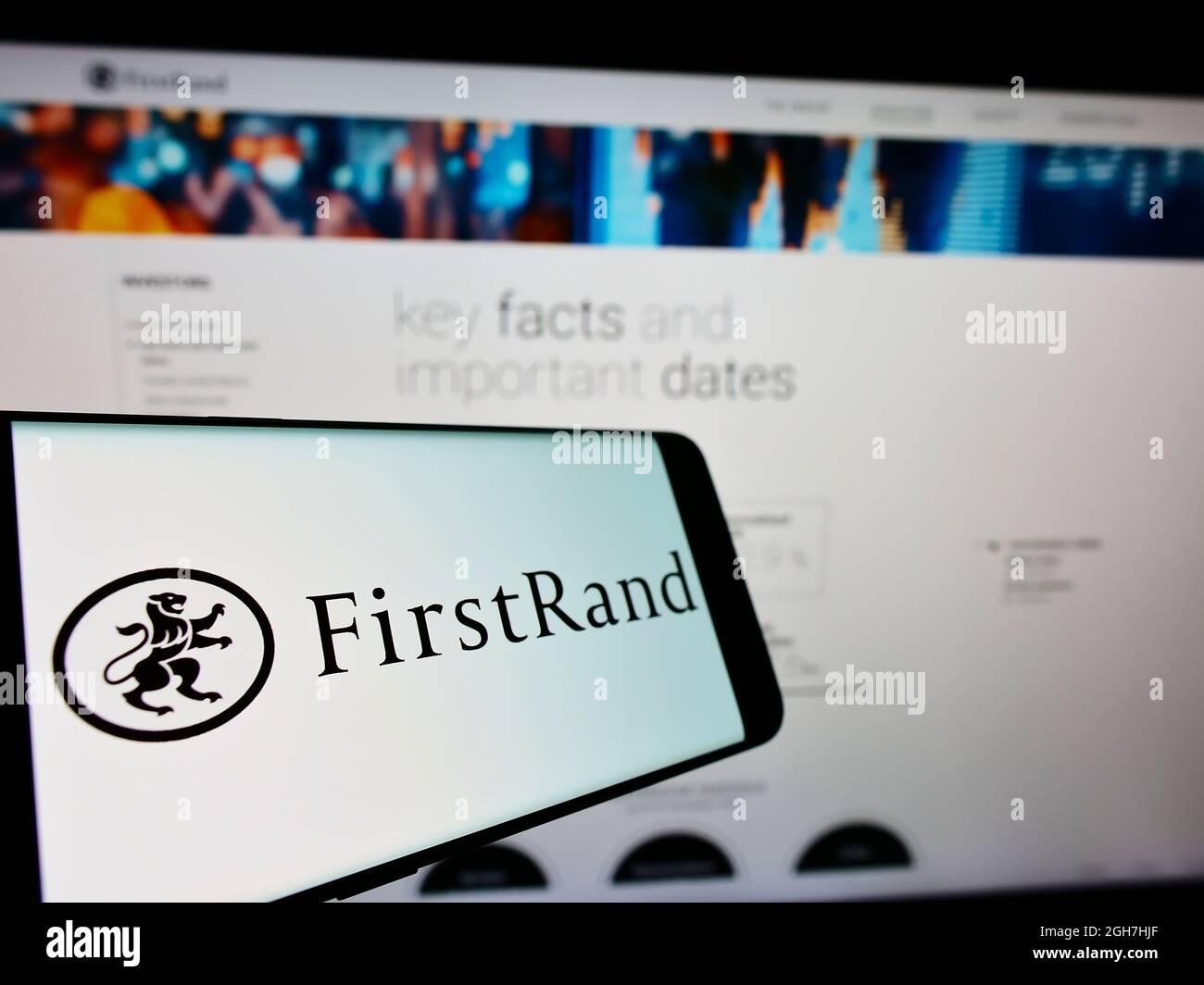 Smartphone con logo della banca sudafricana FirstRand Limited sullo schermo di fronte al sito Web aziendale. Messa a fuoco al centro-sinistra del display del telefono. Foto Stock