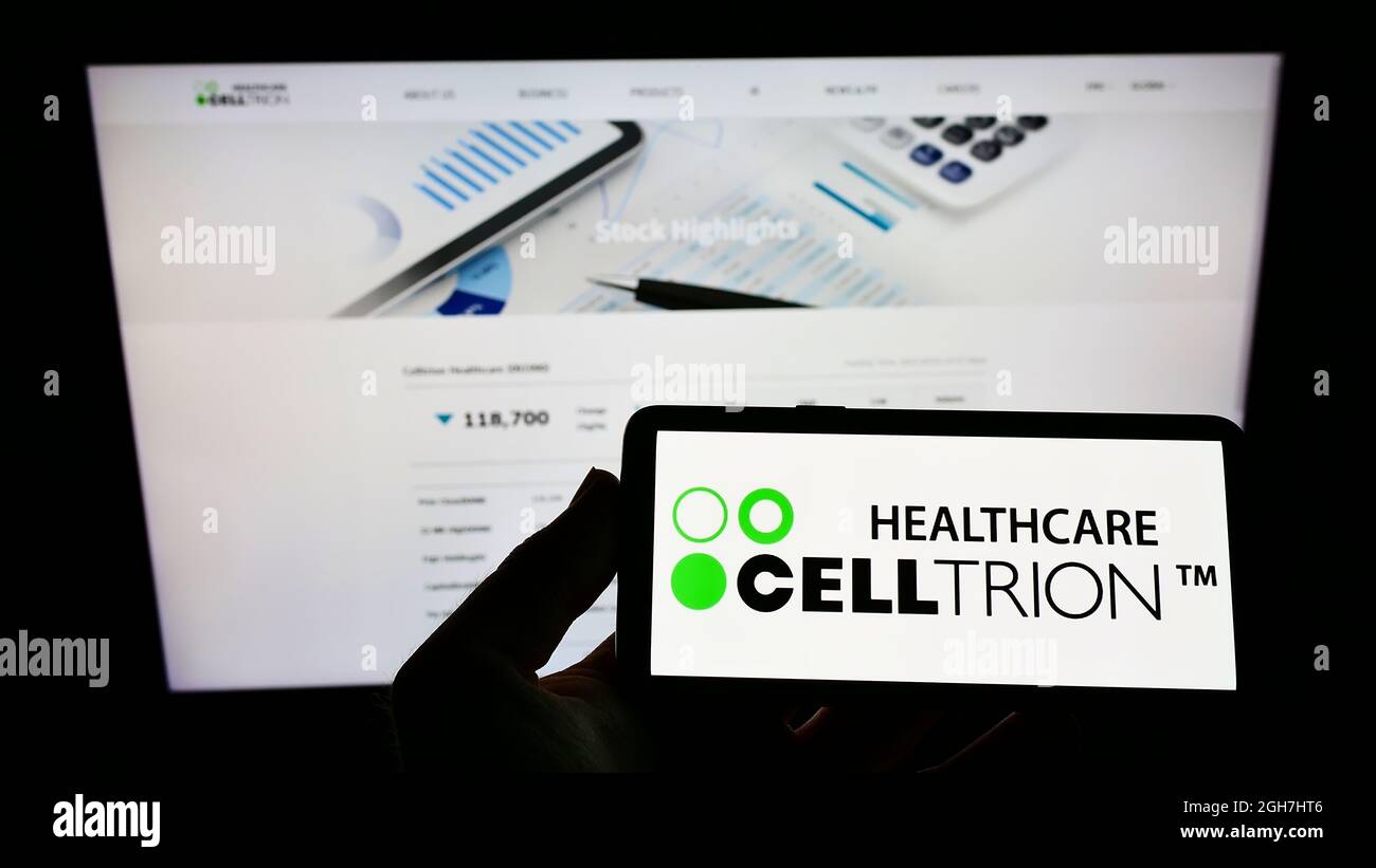 Persona che tiene il cellulare con il logo della società biofarmaceutica Celltrion Inc. Sullo schermo di fronte al sito web aziendale. Mettere a fuoco sul display del telefono. Foto Stock