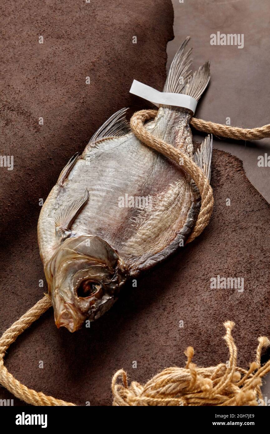 Arrostite secche salate con etichetta di carta sulla coda e corda grossolana su fondo di pelle Foto Stock