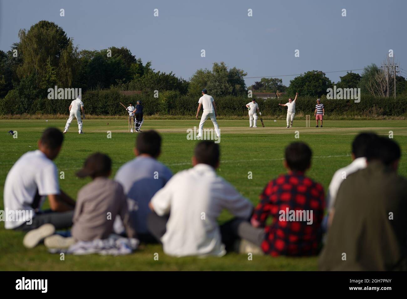 Sono arrivati di recente i cittadini afghani che guardano durante una partita di cricket con i membri del Newport Pagnell Town Cricket Club nel Buckinghamshire, organizzato dal club come un gesto di benvenuto nel Regno Unito. Data foto: Domenica 5 settembre 2021. Foto Stock