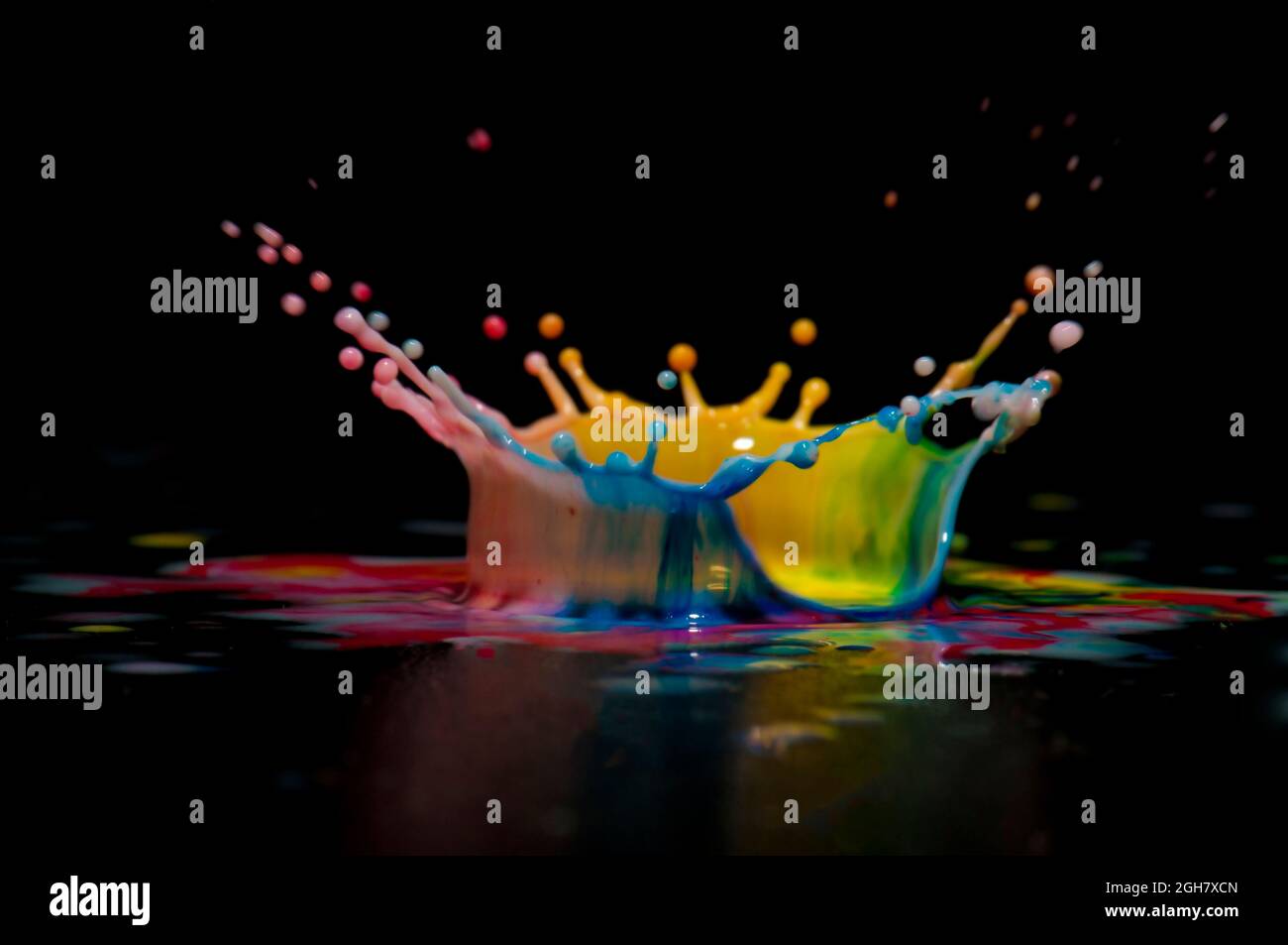 Foto flash ad alta velocità di una goccia di liquido colorata. La gocciolina viene a cadere nel liquido e produce una corona multicolore. Foto Stock