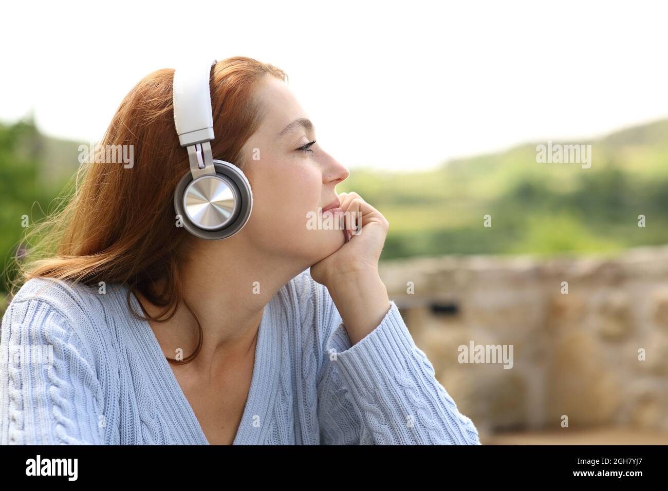 Profilo di una donna che ascolta musica con le cuffie che contempla le viste all'aperto Foto Stock