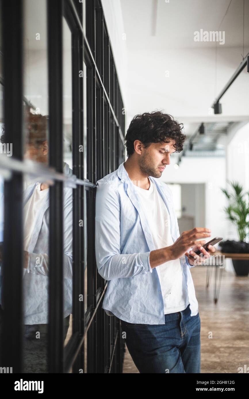 Giovane imprenditore utilizzando smart phone in office Foto Stock