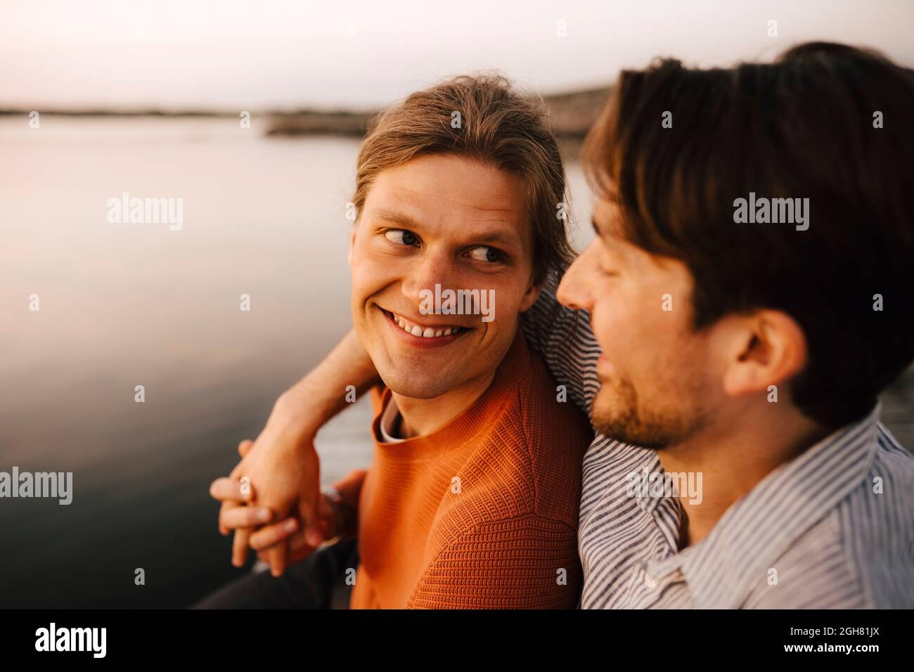 Uomo sorridente con braccio intorno al ragazzo vicino al lago Foto Stock