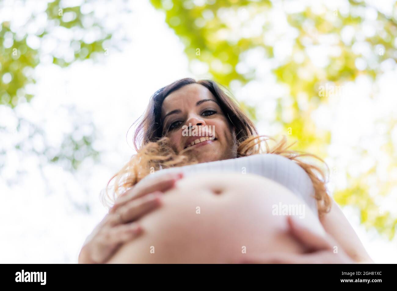 Ritratto a basso angolo del volto sorridente di una donna incinta all'aperto Foto Stock