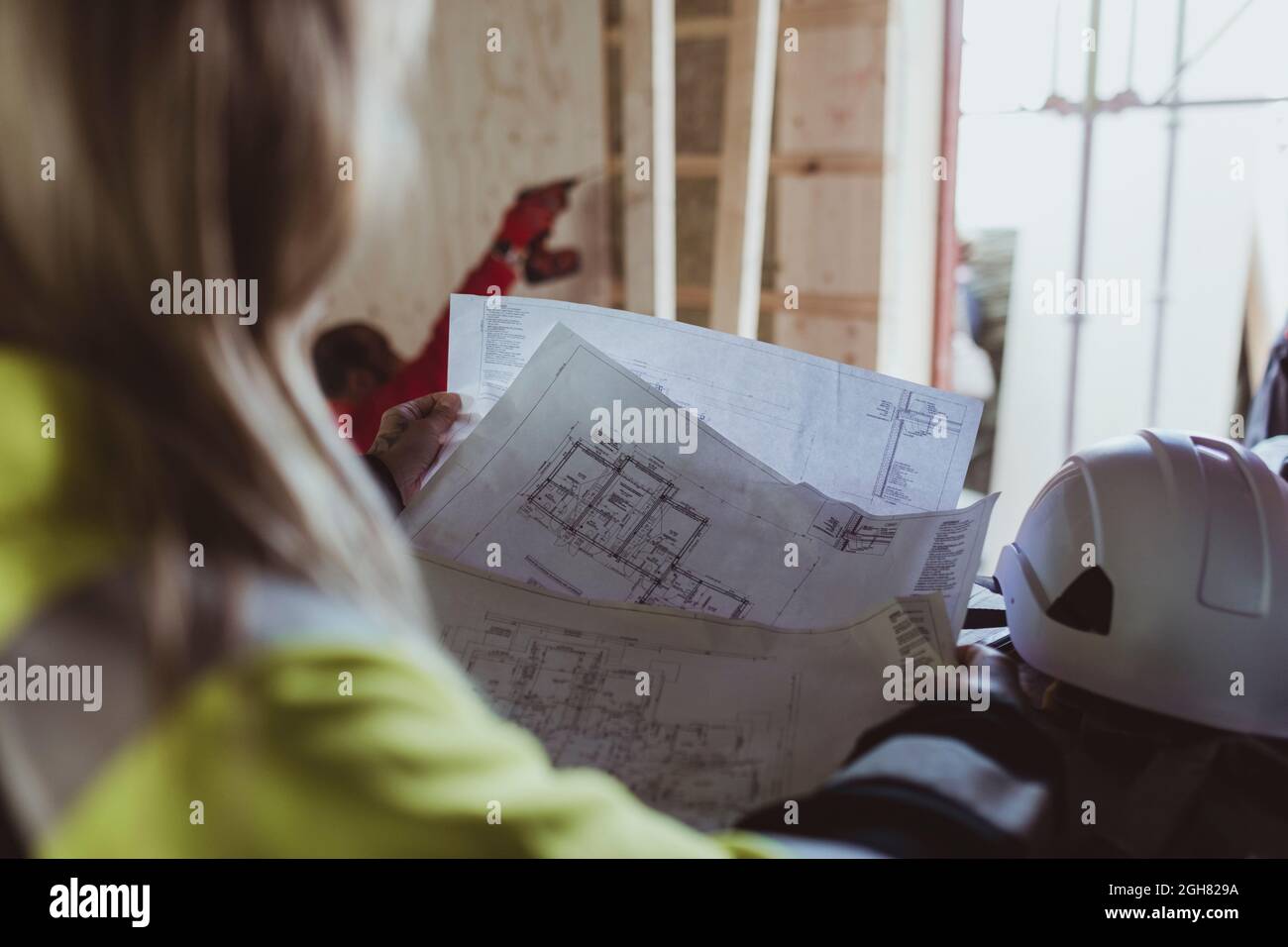 Costruzione femminile lettura piano pavimento durante l'analisi in cantiere Foto Stock