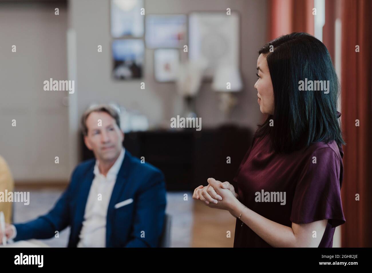 Donna d'affari che discute con i colleghi durante l'incontro al corso di formazione aziendale Foto Stock