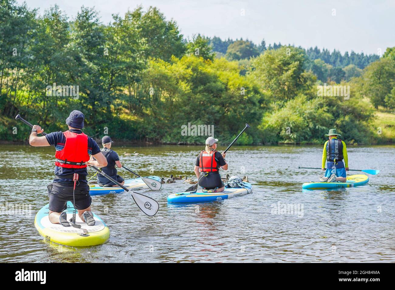 È una domenica e le famiglie sono fuori sul fiume godendo di paddle boarding. Il fuoco è sull'uomo alla sinistra dell'immagine. Foto Stock