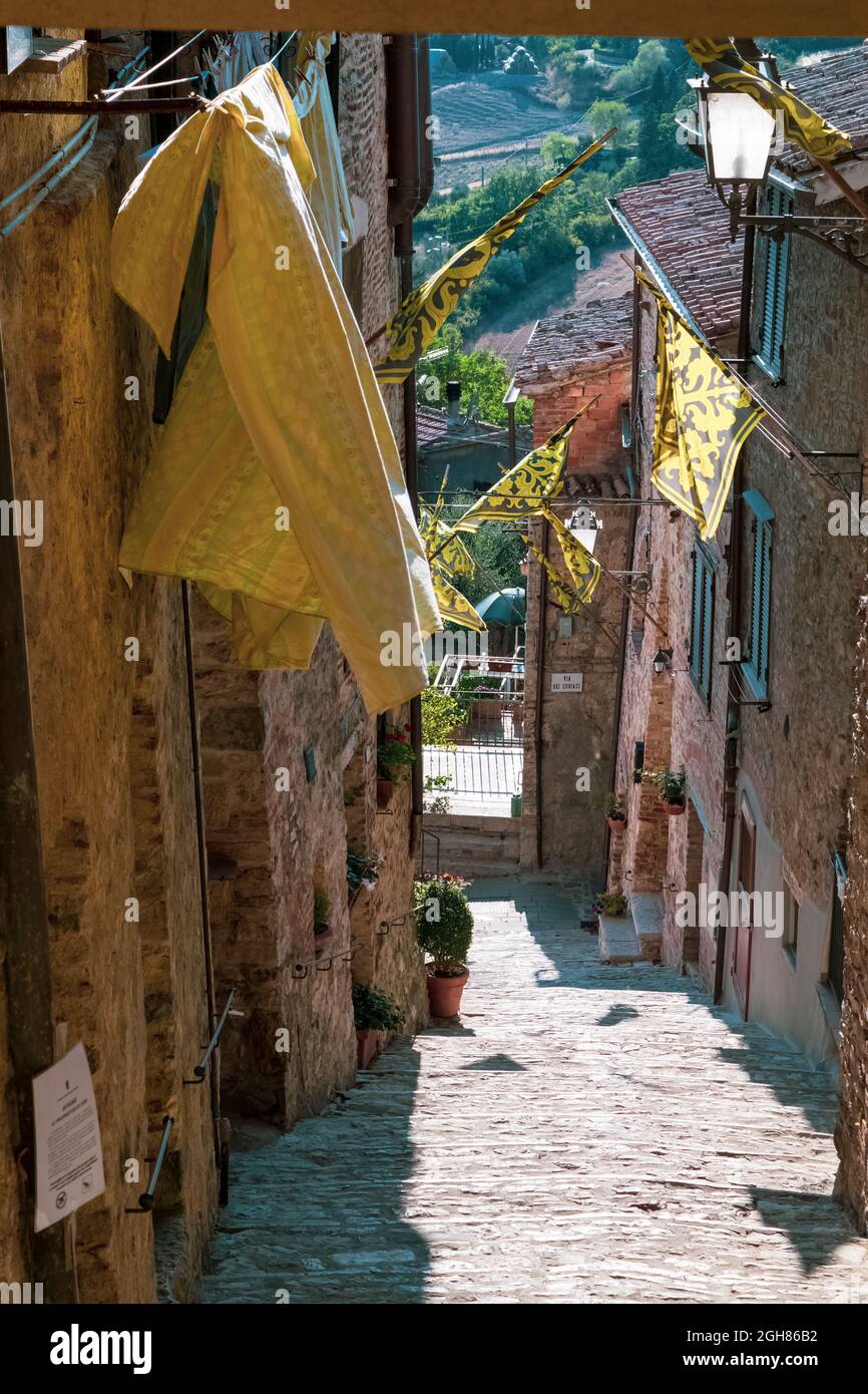 Veduta di una caratteristica strada nel paese di San Casciano dei bagni. Nota le belle bandiere medievali. Siena, Toscana, Italia. Foto Stock