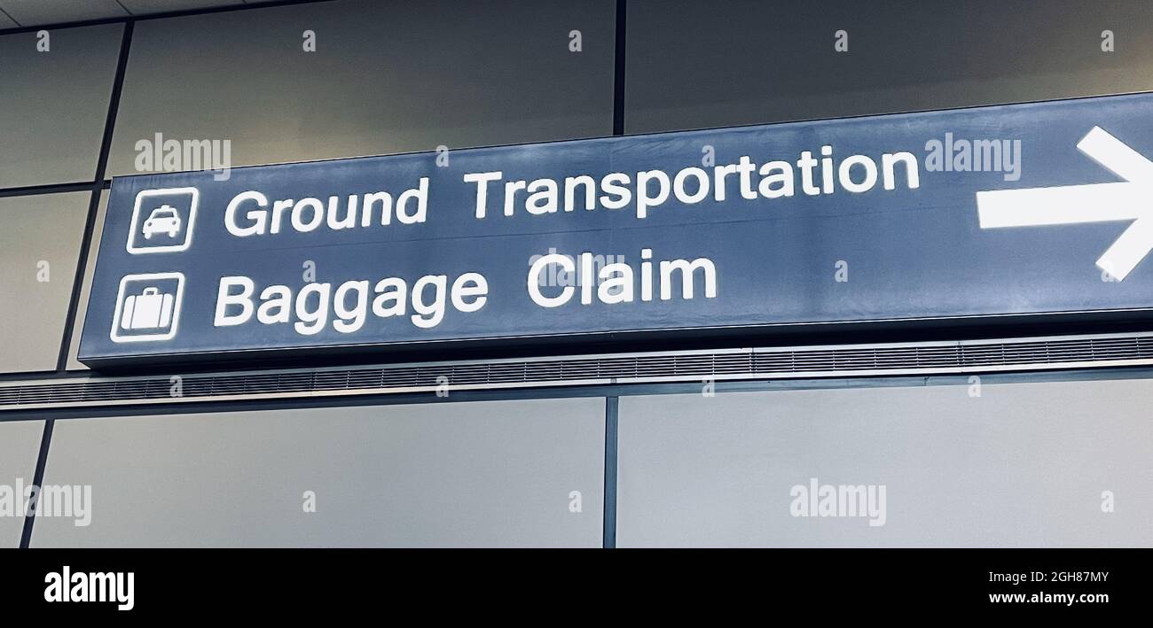 Trasporto a terra e cartello di ritiro bagagli con una freccia in un aeroporto Foto Stock