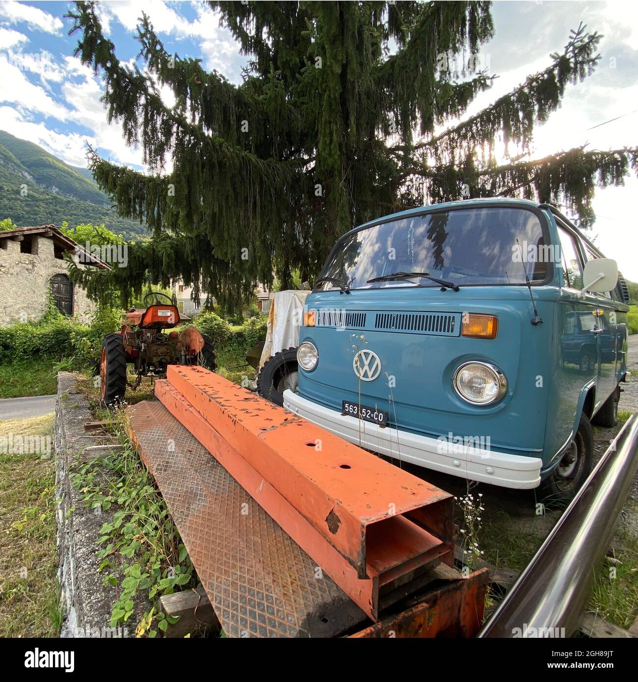 Ein historischer VW Bus T2 mit Kennzeichen von Como parkt an einem Oldtimer Traktor Fiat la piccola aus den 60er Jahren. Foto Stock