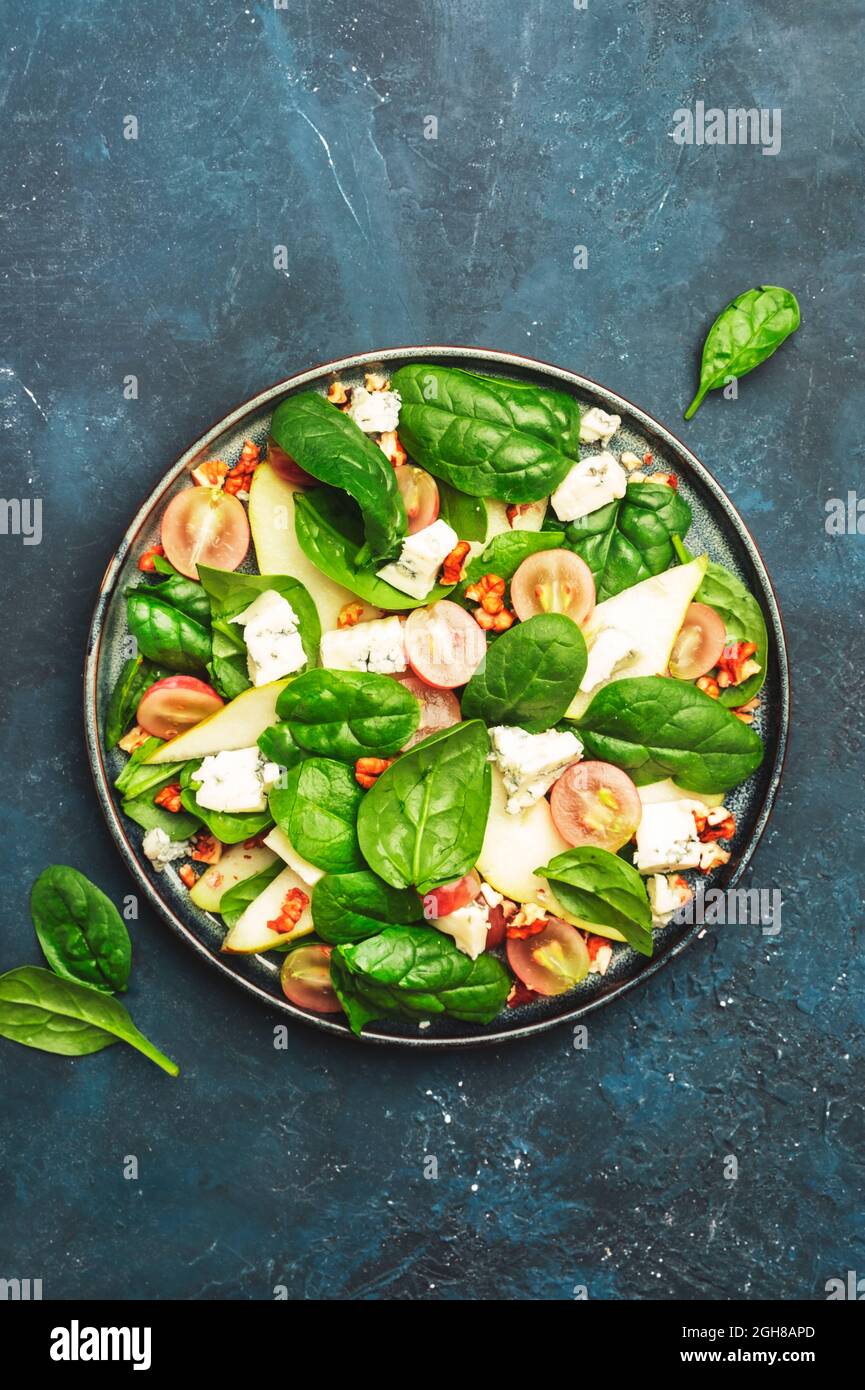 Insalata con pera, formaggio blu, spinaci, uva, noci su sfondo blu, vista dall'alto, spazio copia Foto Stock