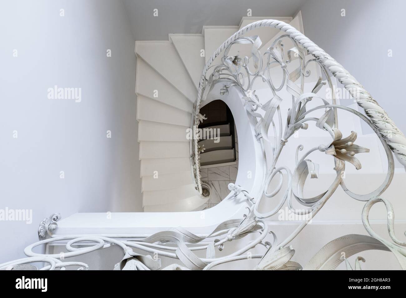 Scale bianche con ringhiere bianche forgiate a spirale come elemento decorativo. Concetto di elementi di interior design Foto Stock