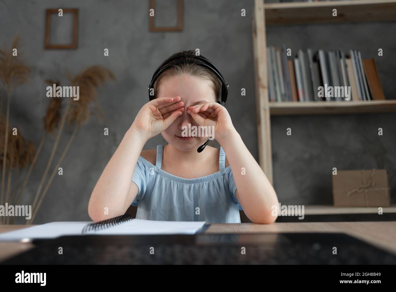 il bambino è stanco di studiare. home insegnamento, compiti. la ragazza strofina gli occhi da fatica, leggere libri e libri di testo. Foto Stock