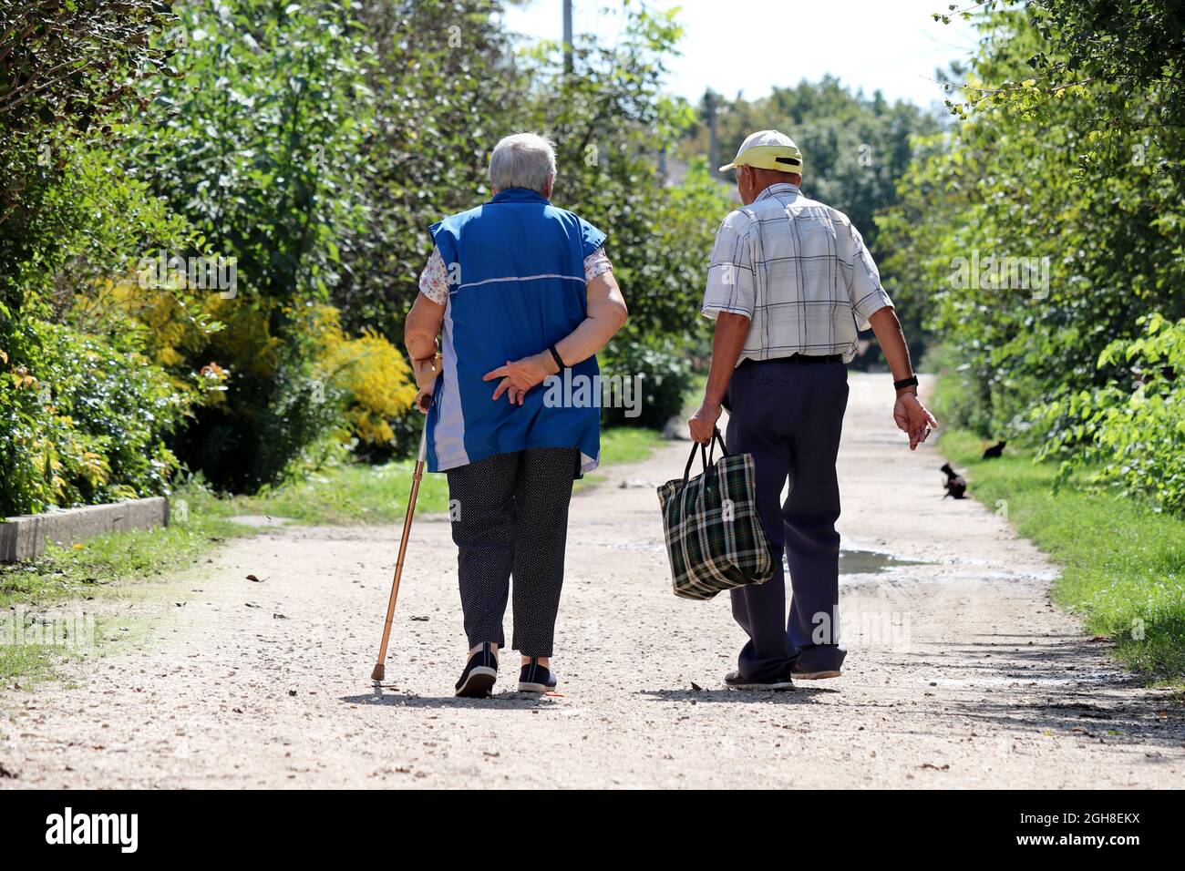 Coppie anziane che camminano o una strada rurale. Uomo anziano e donna con canna insieme, vita in pensione Foto Stock