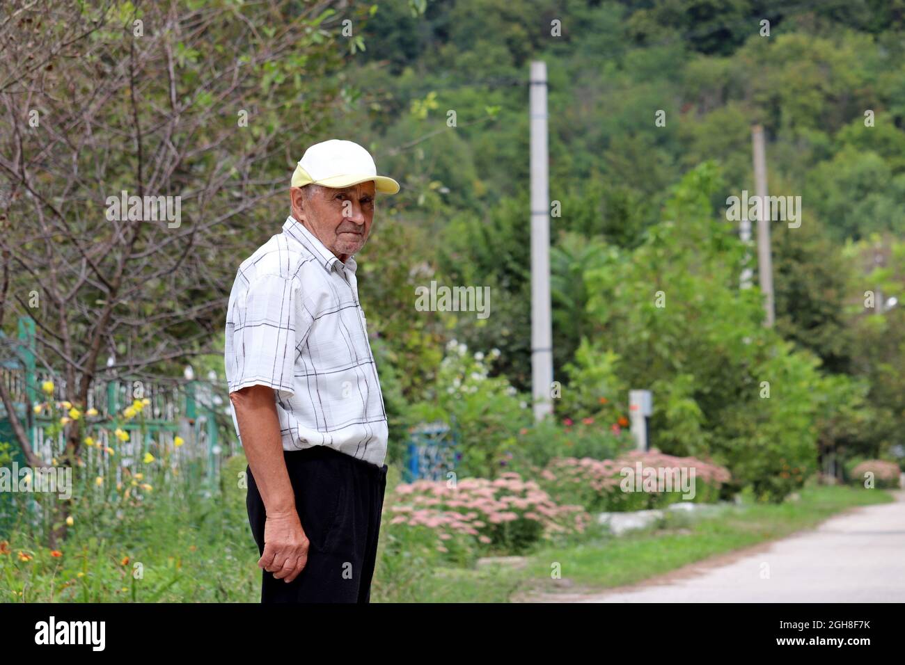 Uomo anziano in piedi su strada rurale. Concetto di vita in villaggio, vecchiaia Foto Stock