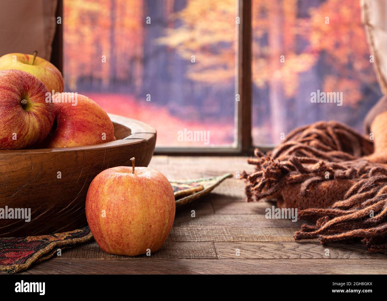 Mele rosse fresche su un tavolo di legno da una finestra con sfondo autmn Foto Stock