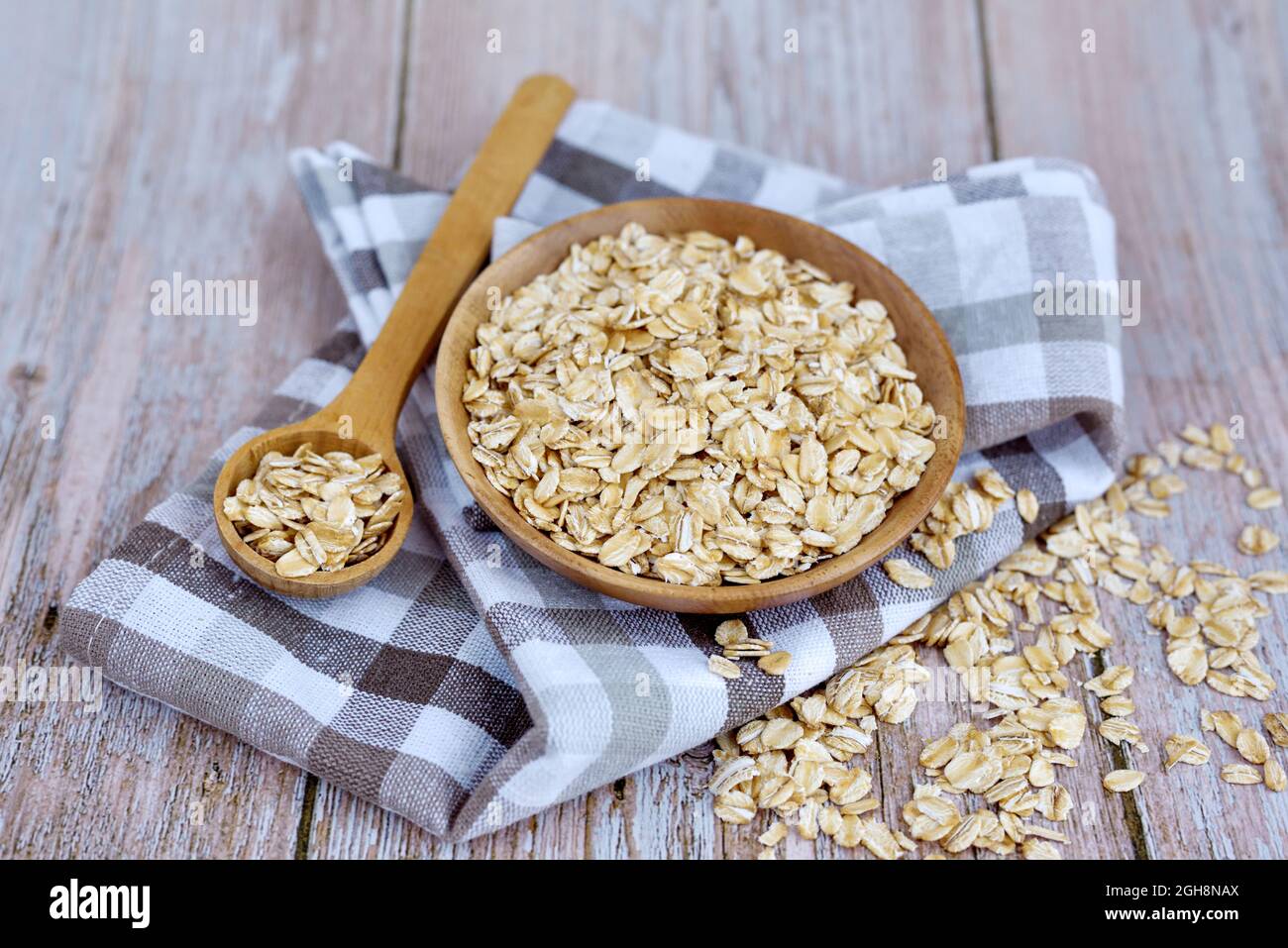 Fiocchi di avena non cotti in ciotola di legno con cucchiaio su tavola rustica. Concetto di alimentazione sana Foto Stock