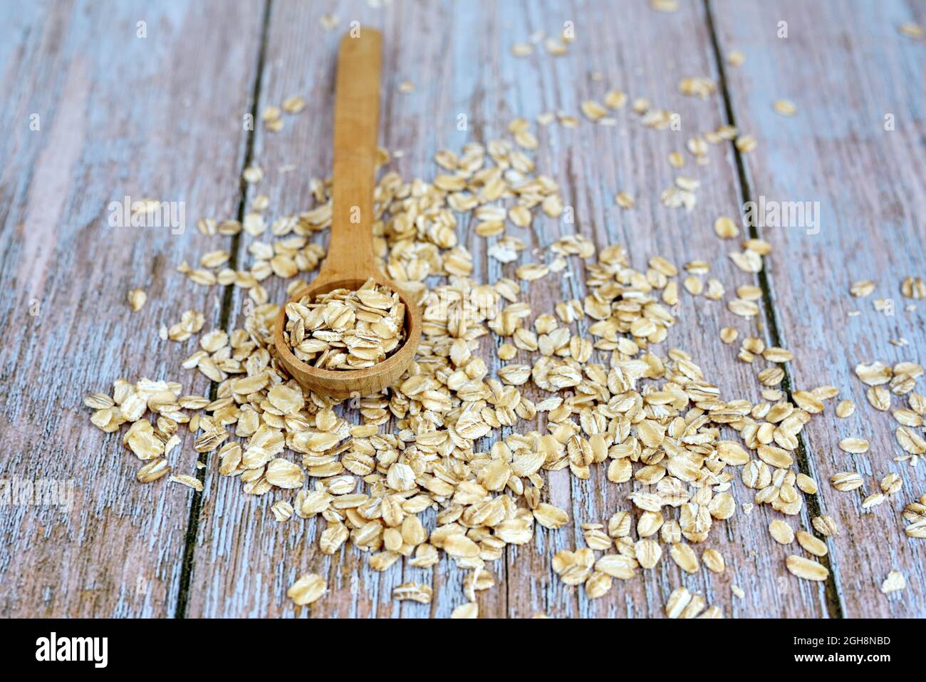 Fiocchi di avena non cotti e un cucchiaio su tavola rustica Foto Stock