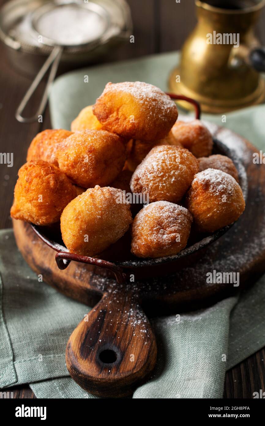 Ciambelle piccole. Biscotti fritti fatti in casa e cosparsi di zucchero a velo in un piatto d'annata su sfondo chiaro. Messa a fuoco selettiva Foto Stock