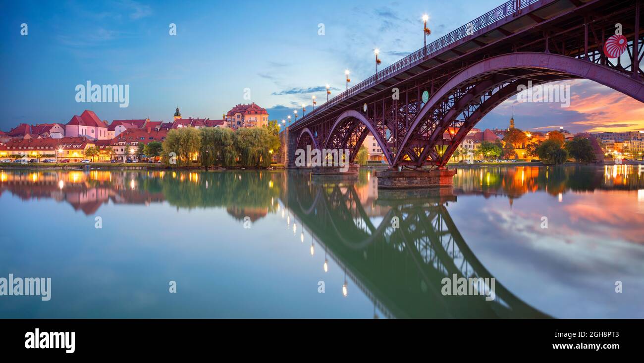 Maribor, Slovenia. Immagine del paesaggio urbano di Maribor, Slovenia all'alba estiva con riflessi della città sul fiume Drava. Foto Stock