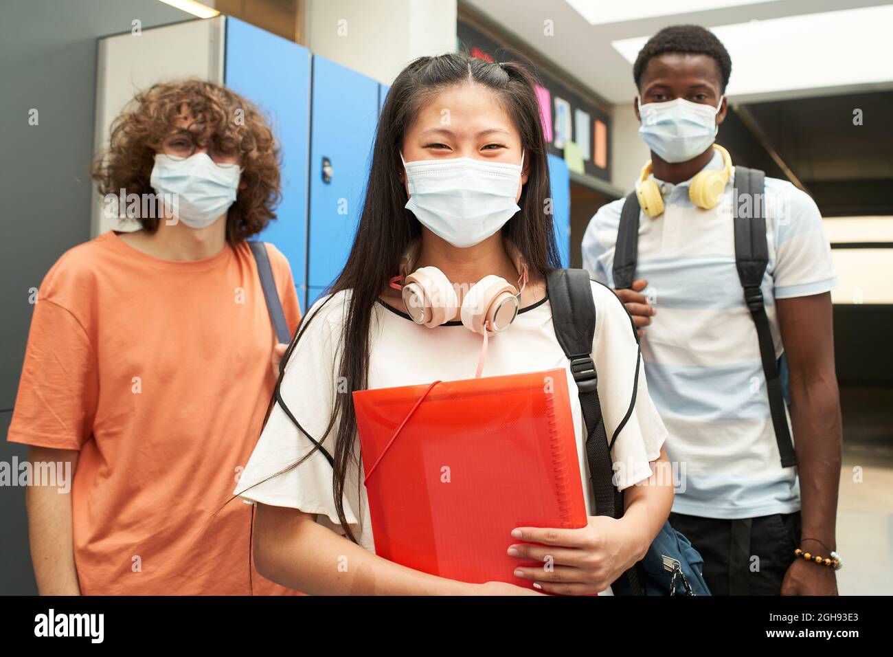 Un gruppo di studenti multirazziali con maschera che guarda la macchina fotografica sorridente. A scuola, mascherato per prevenire e fermare la diffusione del virus corona - Lifestyle Foto Stock