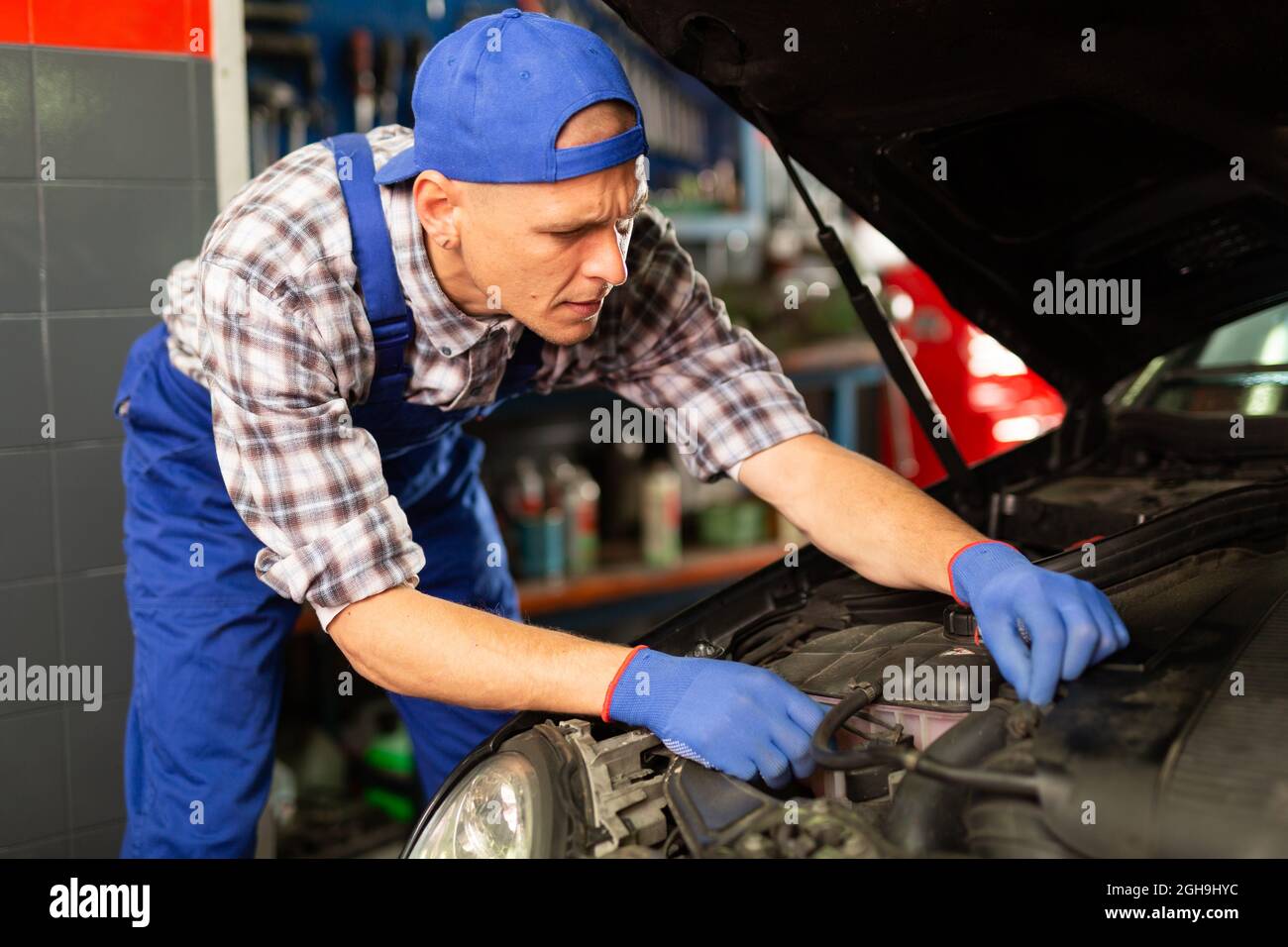 Meccanico che guarda il cofano auto aperto per il controllo interno del  veicolo di manutenzione in officina Foto stock - Alamy