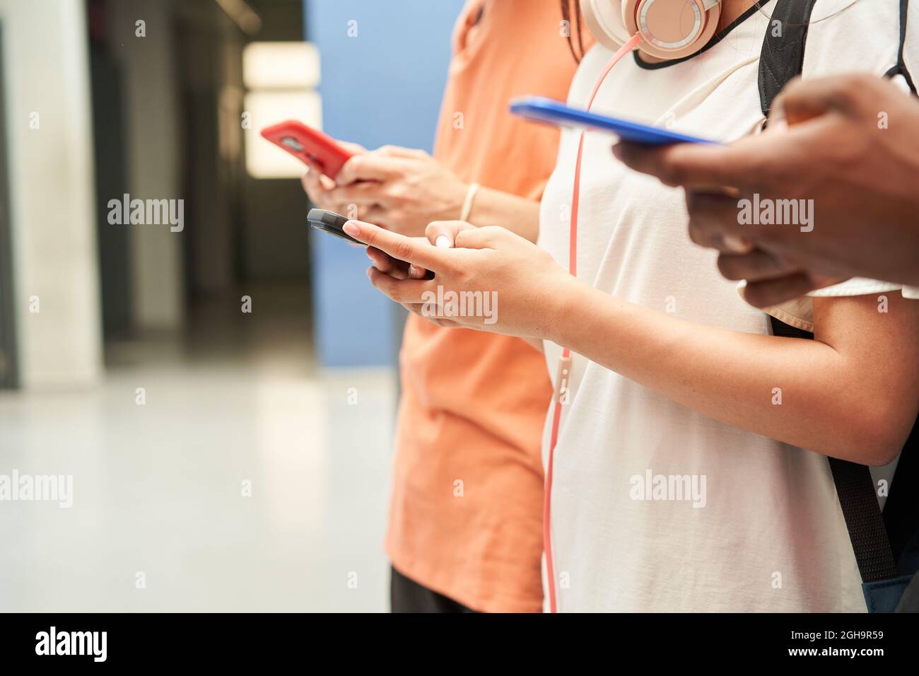 Primo piano delle mani di un gruppo multietnico di studenti irriconoscibili che utilizzano uno smartphone. Persone connesse e sorridenti. Foto Stock
