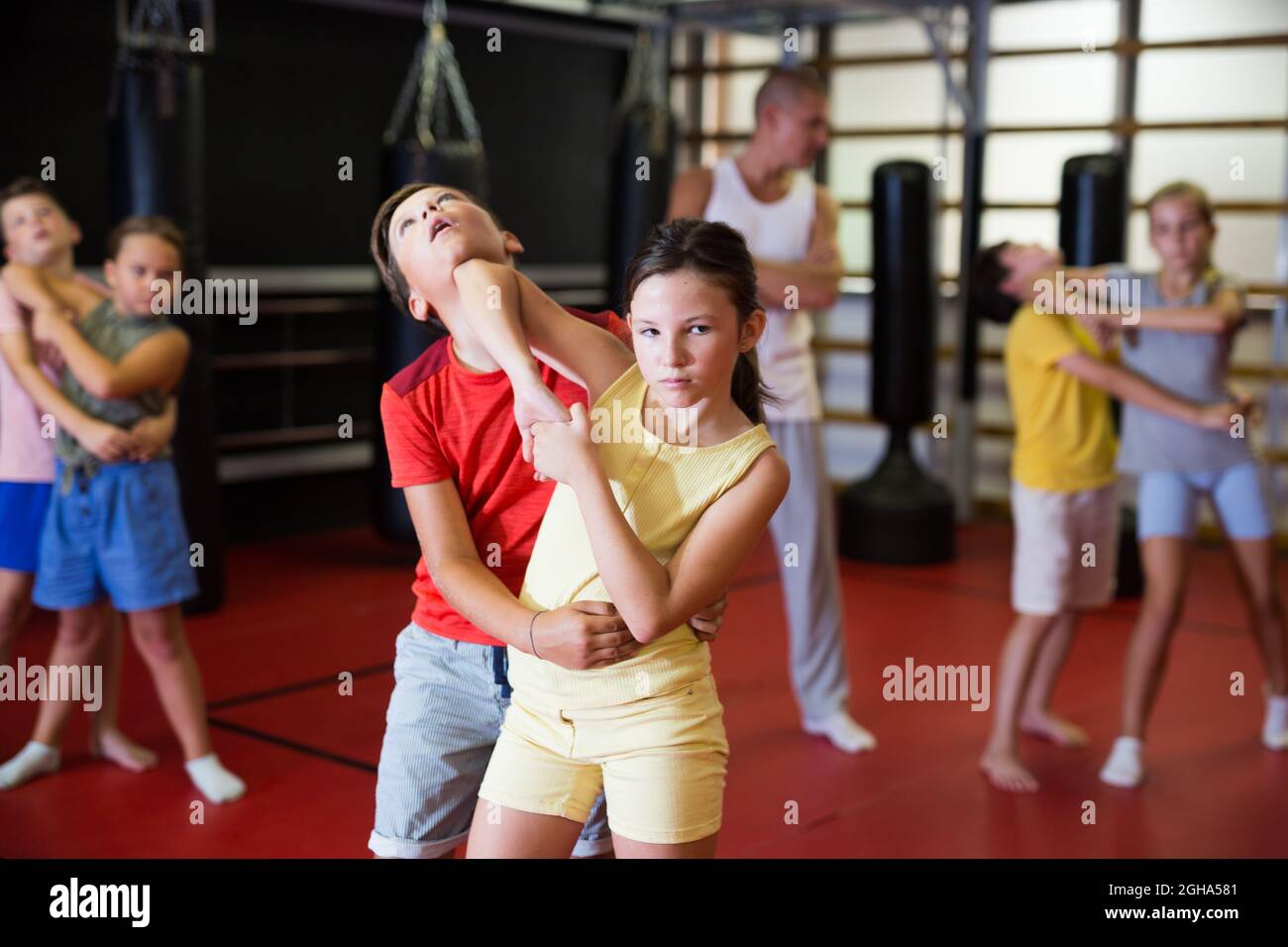 Le ragazze e i ragazzi sportivi sono mosse di autodifesa in coppia in palestra sportiva. Foto Stock